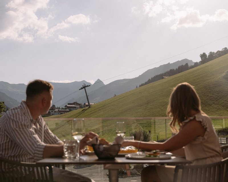 Herbstbiken in Saalbach Hinterglemm Paar sitzt an Tisch und blickt Richtung Berg