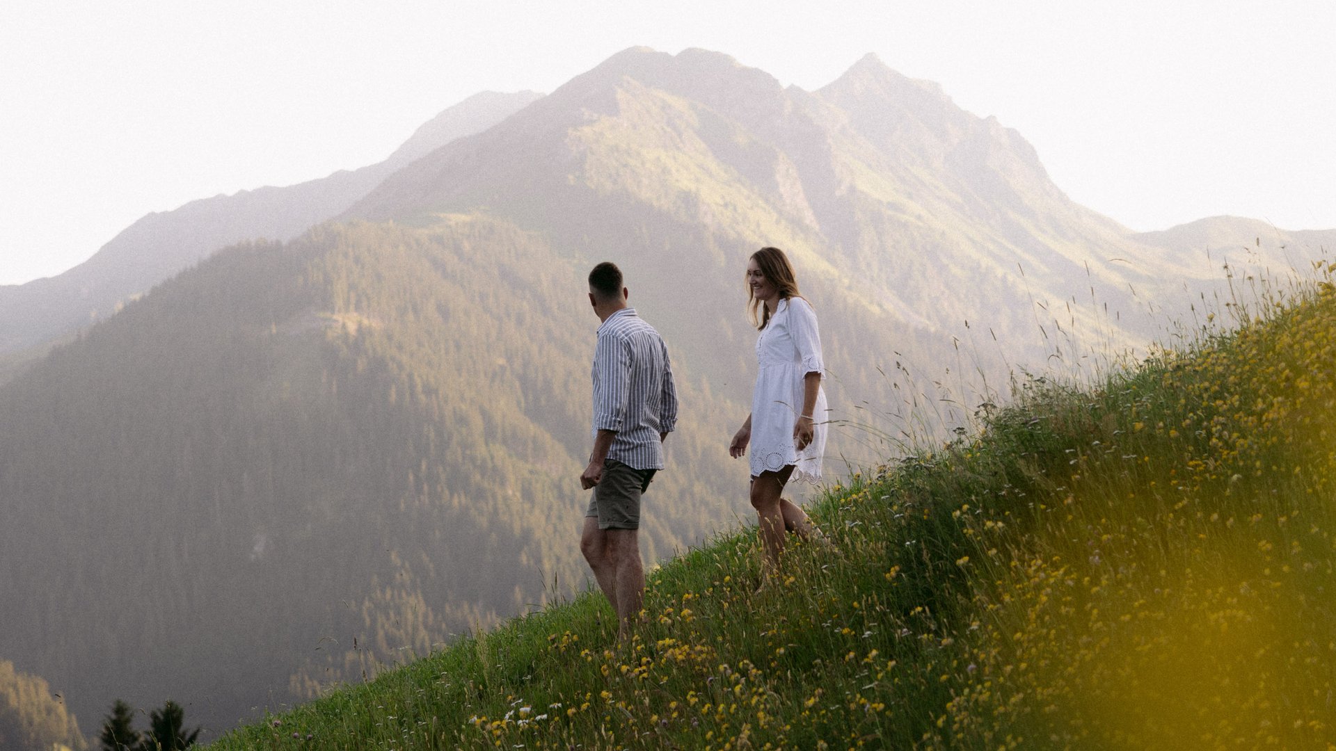 Paar spaziert über Wiese mit Berg im Hintergrund