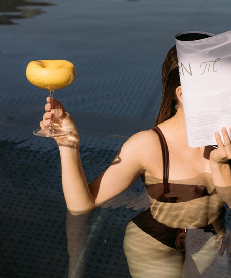 Dame trinkt Cocktail und liest in Pool