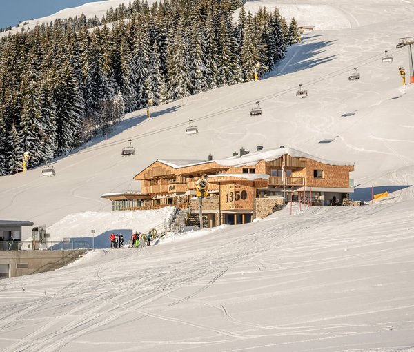 Außenaufnahme von der Alm 1350 im Winter mit Skipiste und Sessellift